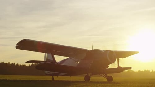 Propeller Airplane is on the Field at Sunset Time