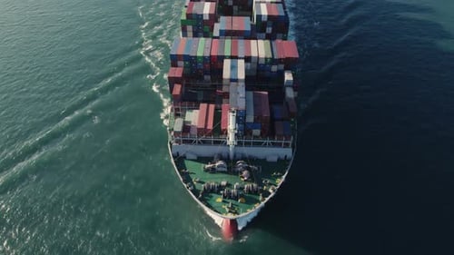 Aerial top view of a loaded container cargo vessel traveling over ocean.