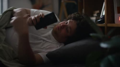 Young Adult in Bed Using Phone
