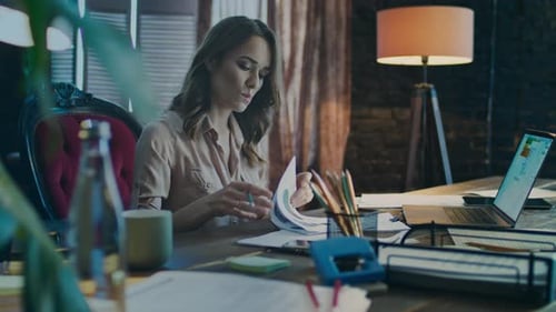 Woman Analyzing Charts at Desk in Office Setting