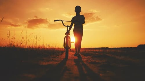 Child Walks with Bike at Golden Sunset Hour