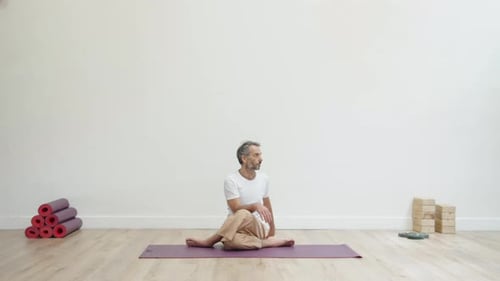 Man Practicing Yoga Twist on Mat Indoors