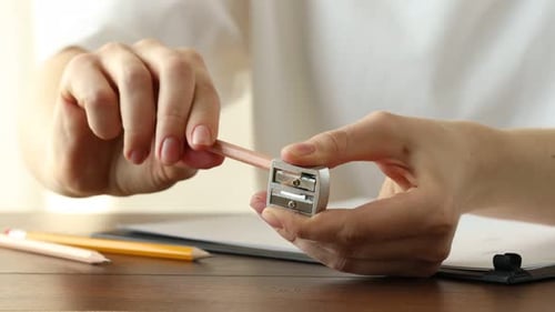 Woman Sharpening Pencil for Drawing at Wooden Desk