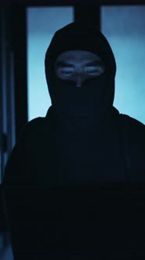 Hooded Figure Using Laptop in Server Room