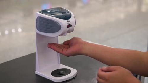 A man uses an automatic alcohol hand sanitizer gel dispenser machine as prevention against covid-19