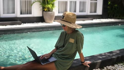 Woman Sitting in Near the Swimming Pool Using Laptop