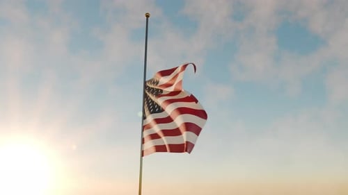 Bandera estadounidense a media asta contra el cielo del atardecer