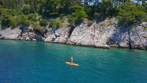 Young Woman on a Stand Up Paddle Board SUP Rawing Among Beatyful Rocks