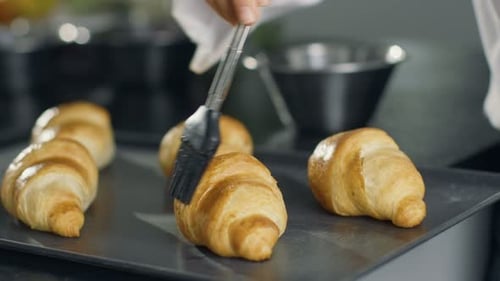 Glazing Freshly Baked Croissants on a Tray