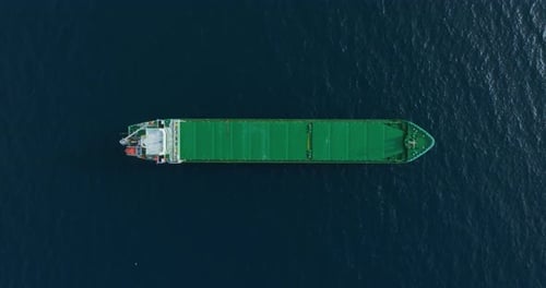 Luftaufnahme von oben nach unten, grünes großes Stückgutschiff, das auf See vor Anker liegt