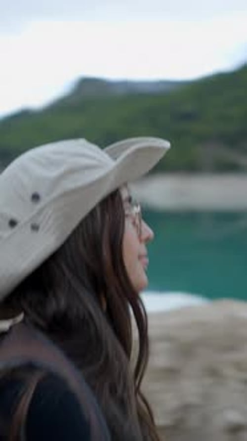Girl with Backpack Hikes By Still Lake and Takes Out Phone Follow Pan