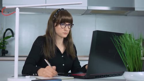 Smiling Businesswoman Working on Laptop Computer at Home Office Female Professional Writing Notes in