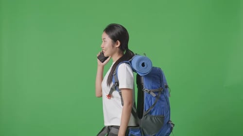 Side View Of Female Hiker Talking On Smartphone And Looking Around While Walking On Green Screen