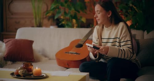 Woman Playing Guitar on Couch Indoors