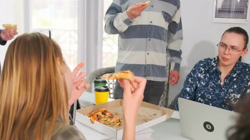Group of Young People Eating Pizza and Drinking Coffee in Modern Office