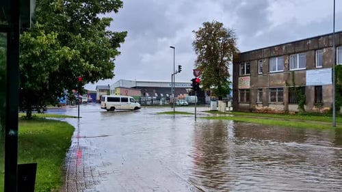 Wide shot of a flooded street with cars driving through watery intersection