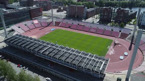 Aerial tilt flyover of sunny green football soccer stadium pitch