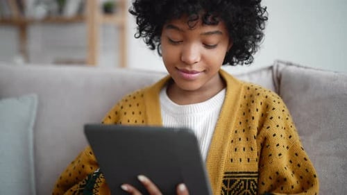 Young Adult Using Tablet at Home on Sofa