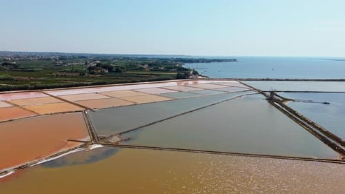 Forward drone flight over colorful salt pans in Sicily by sea