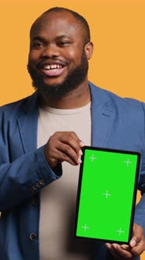 Vertical Video Amused Man Laughing While Presenting Tablet with Green Screen Display