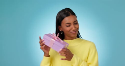 Woman, smile and shake gift box in studio for birthday present, product deal