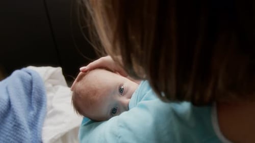 Loving Mother Cradling Newborn Baby in Natural Light