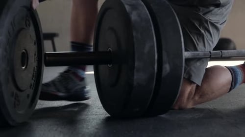 Close Up Man Loading Weight Plates Onto Barbell at Gym 3539 Years