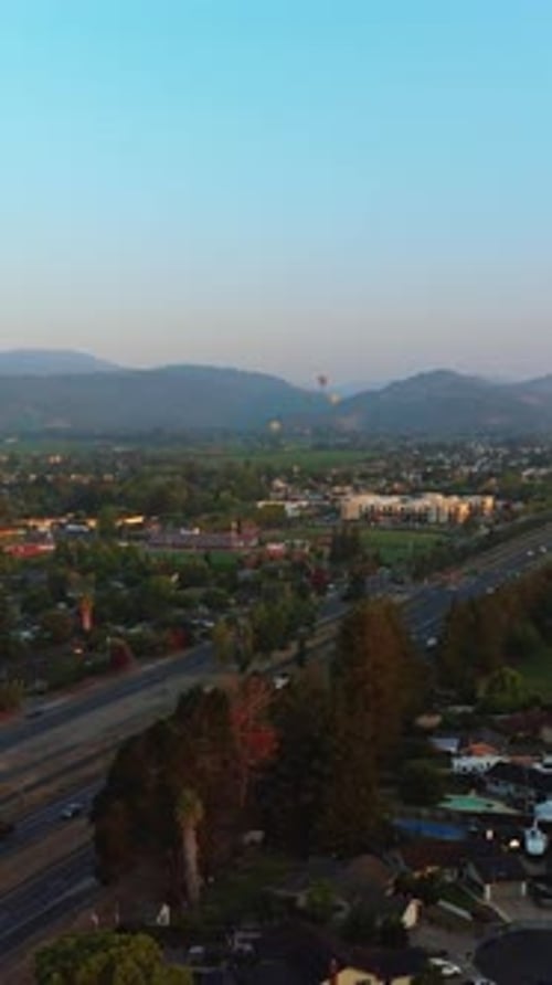 Roads full of cars in Napa, California, USA. Hot air balloons in the air over the city.