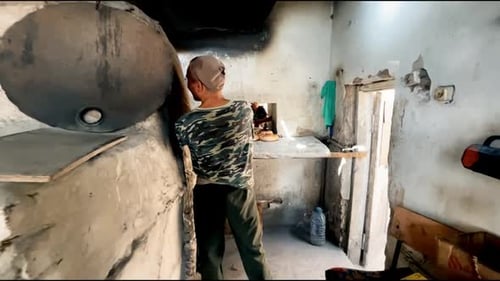 A baker bakes bread in a cheap bakery