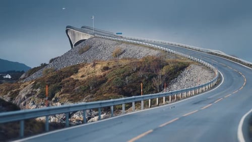 Iconic Storseisundet Bridge on the Atlantic ocean road. Seagulls fly low. Slow-motion, pan forward.