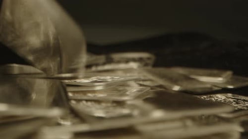 Beautiful close up of a lot of silver bars falling on a velvet fabric in slow motion