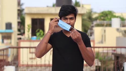 Young Adult Puts On a Surgical Mask and Approves