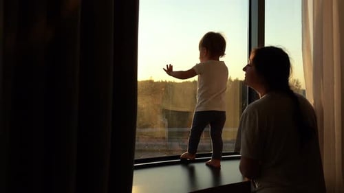 Toddler and Adult Silhouetted Against Sunny Window
