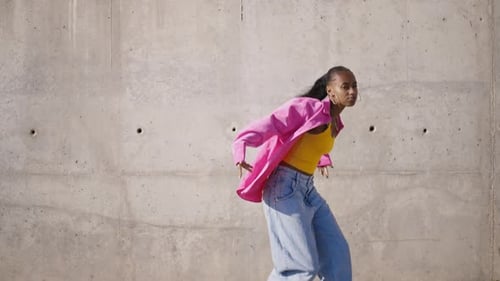 Stylish Woman Dancing in Front of Concrete Wall