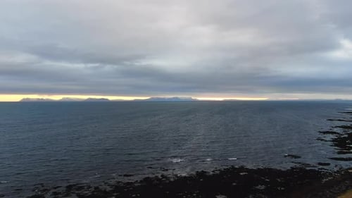 Aerial view from the sea with a sunset and cloudy sky.