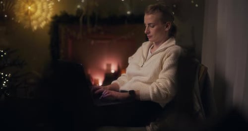 Frau arbeitet nachts an einem Laptop und schreibt eine E-Mail gegen den Weihnachtsbaum