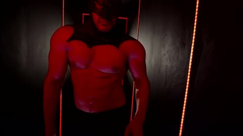 Muskulser Mann mit sexy nacktem Torso und schwarzer Latexmaske eines Superhelden auf dem Kopf, der sich verfhrerisch bewegt Muskulser Mann mit sexy nacktem Torso und schwarzer Latexmaske eines Superhelden auf dem Kopf, der sich verfhrerisch bewegt
