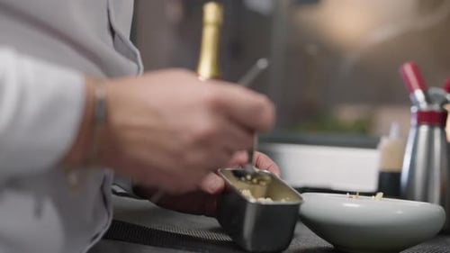 Side view of a chef garnishing a dish at a kitchen of a French chef restaurant with burred backgroun