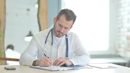 Doctor Working on Medical Report and Laptop in Clinic