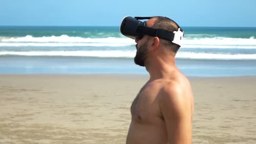 Handsome caucasian man smiles enjoying virtual reality headset on sunny summer beach