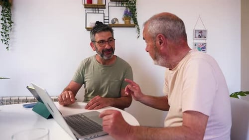 Two Men Discussing Information Shown on a Laptop
