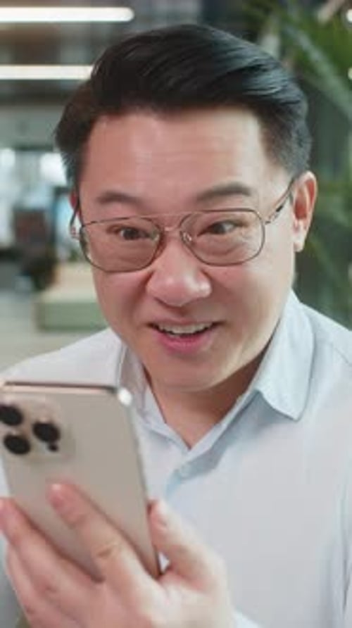 Amazed Businessman Using Smartphone Shocked By Sudden Victory Lottery Win in Modern Office Lobby