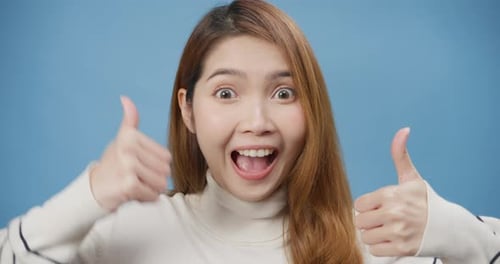 Asia lady wear sweater stand show thumb up over isolate blue background happy face show perfec.