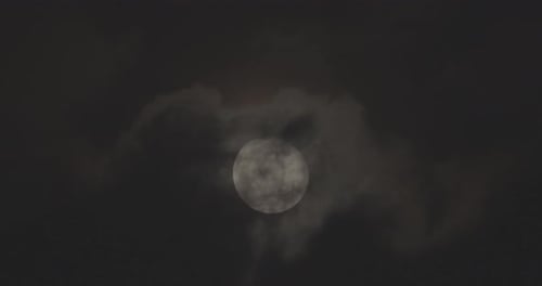 A full moon in a sky with clouds moving
