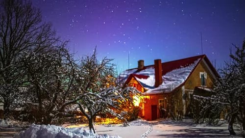 A wintry Christmas landscape with a snowy house and garden under a clear starry sky. Time lapse