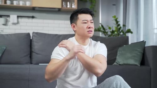 Adult Man Massages Sore Shoulder at Home