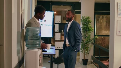 Businessmen Chatting by Water Cooler in Modern Office
