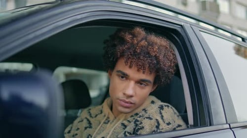 Young Adult Sitting in a Car in Urban Setting