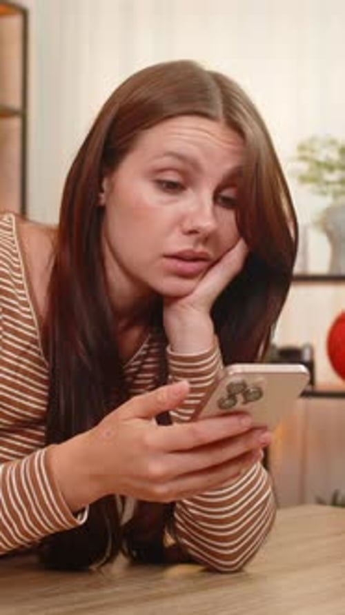 Bored Woman Scrolling on Phone Lying on Table