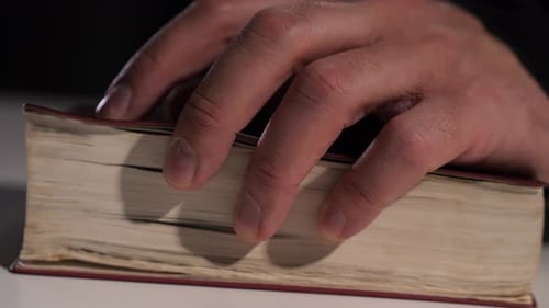 Hand Holding Open Thick, Old Book